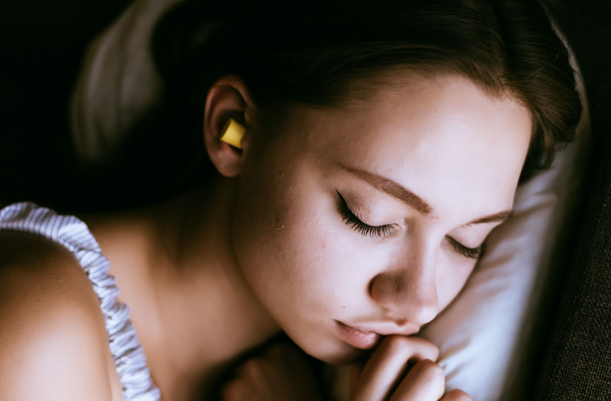 Wanita tidur menggunakan earplug